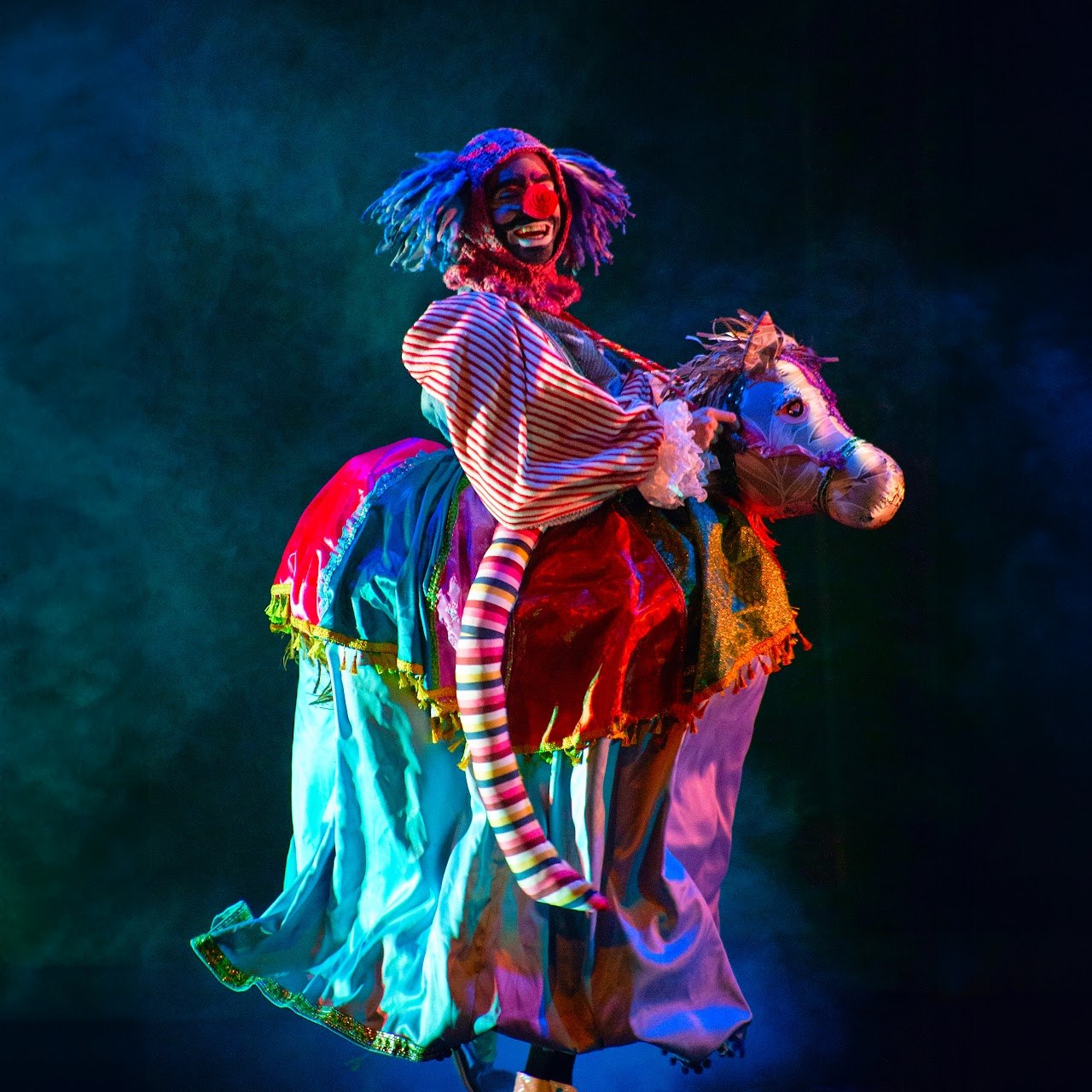 Personaje de payaso de circo montado en caballito de juguete en la obra Legatus y Dimittas — Colectivo Pies Hinchados